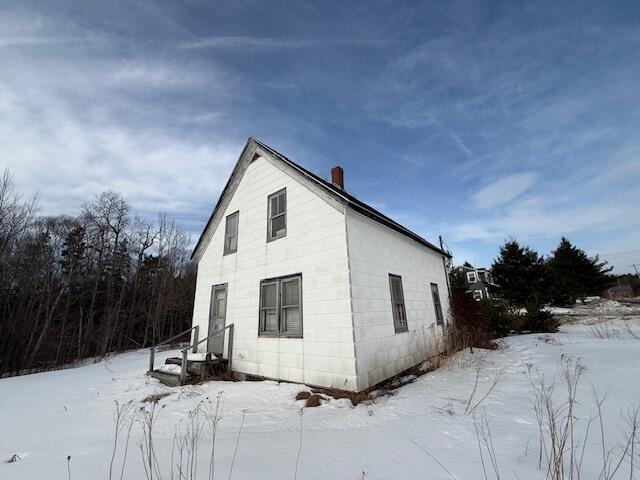 view of snowy exterior with a chimney