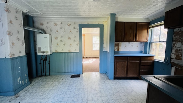 kitchen featuring an ornate ceiling, water heater, a wainscoted wall, and wallpapered walls