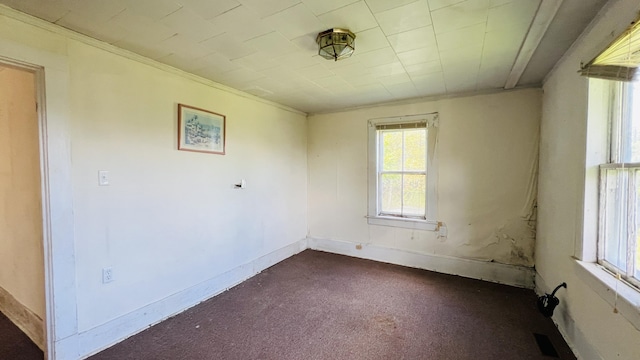 spare room featuring ornamental molding, visible vents, dark carpet, and baseboards