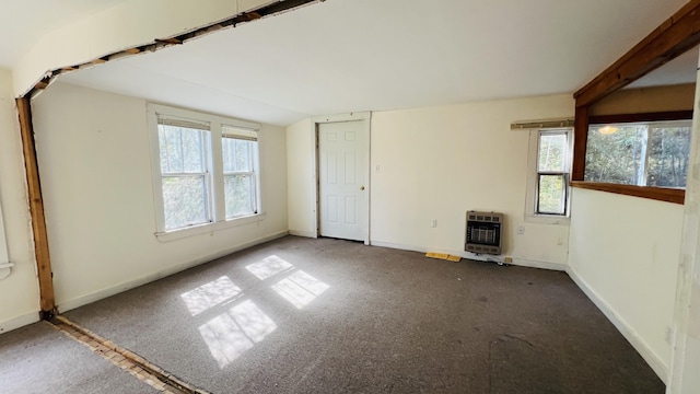 carpeted empty room featuring baseboards, plenty of natural light, and heating unit