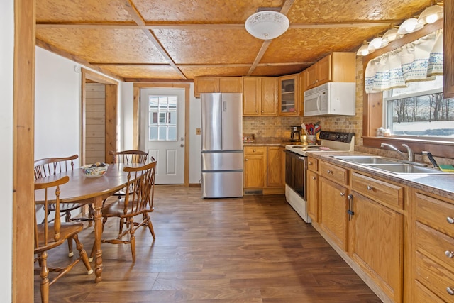 kitchen with white appliances, dark wood finished floors, brown cabinetry, glass insert cabinets, and a sink