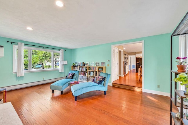 living area with baseboard heating, recessed lighting, light wood-style flooring, and baseboards