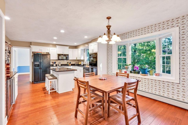 dining space with a baseboard heating unit, light wood-type flooring, a chandelier, and recessed lighting