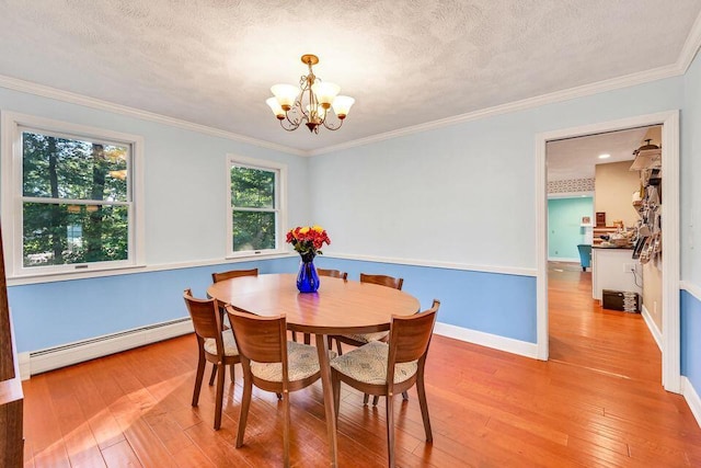 dining area featuring a textured ceiling, a notable chandelier, a baseboard heating unit, light wood-type flooring, and crown molding