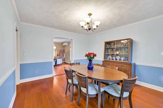 dining area with a chandelier, a textured ceiling, wood finished floors, baseboards, and a wall mounted air conditioner