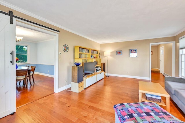 living room with baseboards, a barn door, wood finished floors, and crown molding