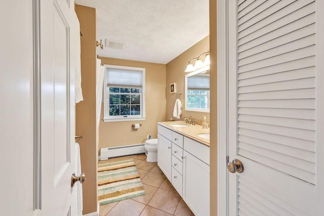 bathroom with tile patterned flooring, a baseboard heating unit, a sink, a closet, and double vanity