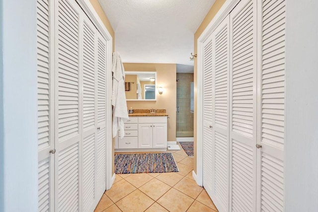 hallway featuring a sink, light tile patterned floors, and a textured ceiling