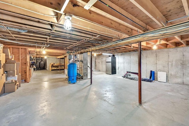 unfinished basement featuring freestanding refrigerator