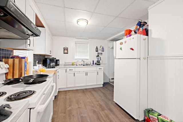 kitchen featuring white appliances, a sink, under cabinet range hood, light wood-type flooring, and baseboard heating