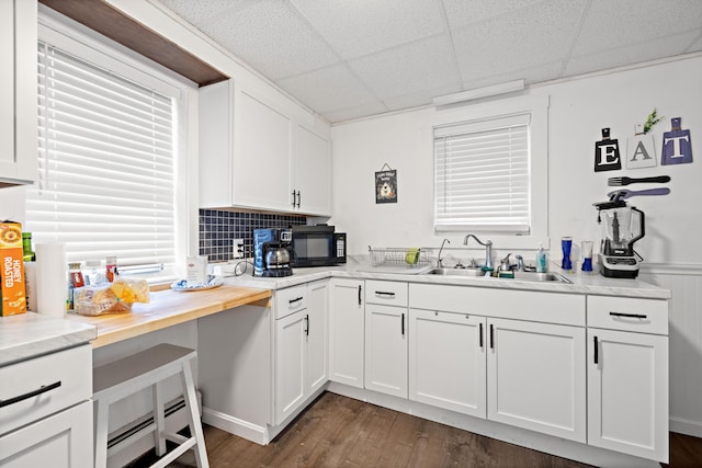 kitchen featuring a sink, dark wood-type flooring, white cabinets, a paneled ceiling, and black microwave