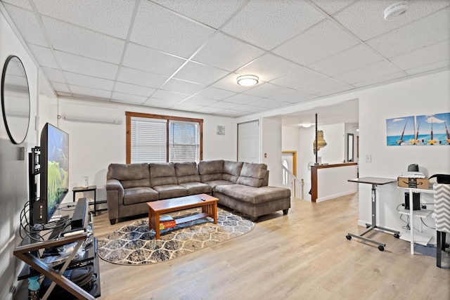 living room featuring wood finished floors, a wall mounted air conditioner, and a paneled ceiling