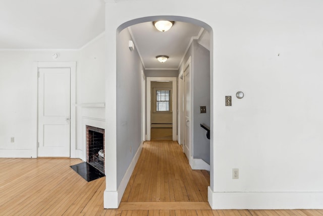 hall with ornamental molding, arched walkways, baseboards, and hardwood / wood-style floors