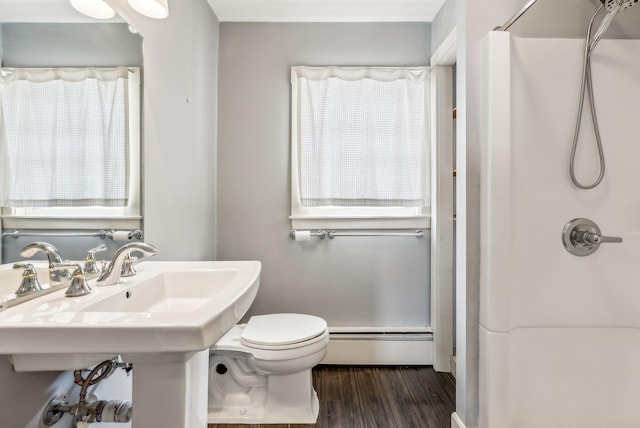 bathroom with curtained shower, baseboard heating, wood finished floors, and toilet