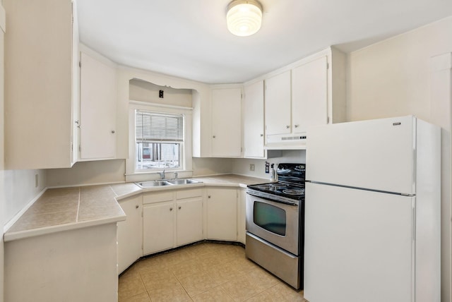 kitchen with stainless steel electric range, white cabinetry, light countertops, and freestanding refrigerator