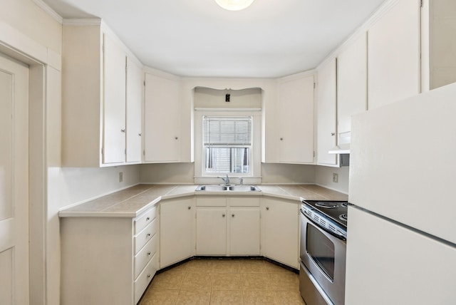 kitchen with freestanding refrigerator, white cabinets, a sink, and stainless steel electric range