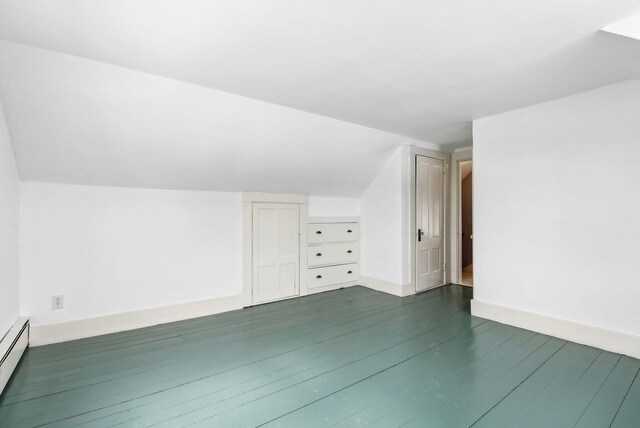 additional living space featuring dark wood-type flooring, baseboard heating, vaulted ceiling, and baseboards