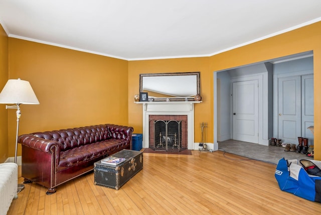 living room featuring ornamental molding, a brick fireplace, and hardwood / wood-style floors