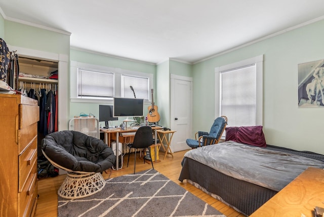 bedroom featuring light wood finished floors, a closet, and crown molding