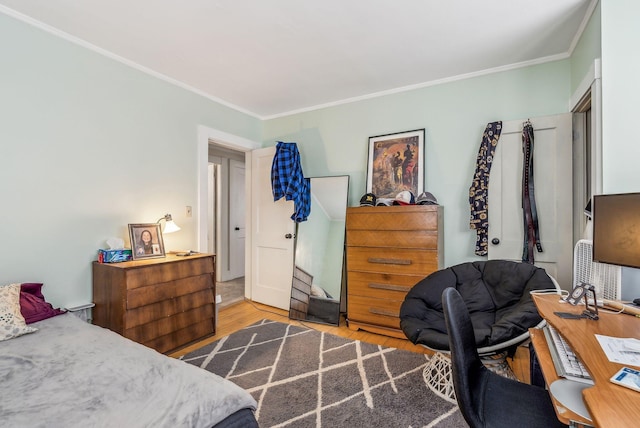 bedroom with ornamental molding and wood finished floors