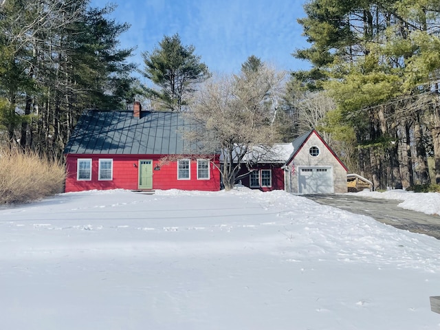 exterior space featuring a garage, a standing seam roof, metal roof, and a chimney