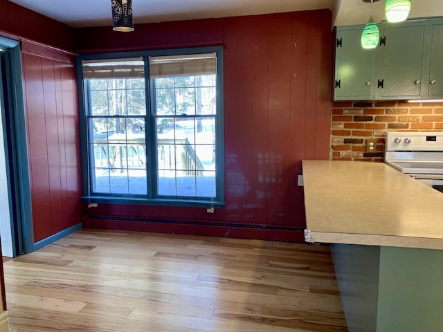 kitchen featuring electric stove, hanging light fixtures, light countertops, light wood-style floors, and green cabinets