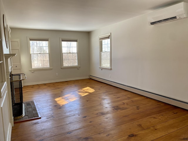 unfurnished living room featuring a fireplace, a baseboard heating unit, a wall mounted air conditioner, baseboards, and hardwood / wood-style flooring