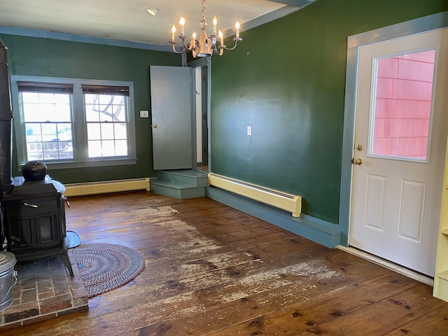 interior space with a wood stove, a notable chandelier, a baseboard heating unit, and dark wood-type flooring