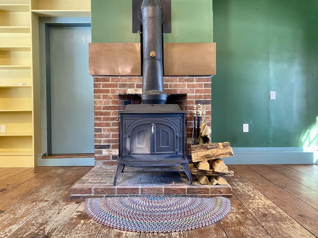 interior details featuring wood finished floors, a wood stove, and baseboards