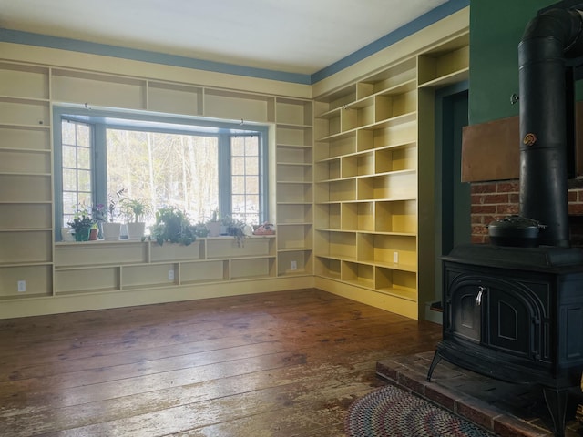 sitting room featuring built in features, a wood stove, and dark wood finished floors