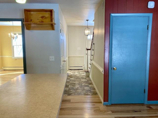 hall featuring a baseboard radiator, visible vents, a notable chandelier, and wood finished floors