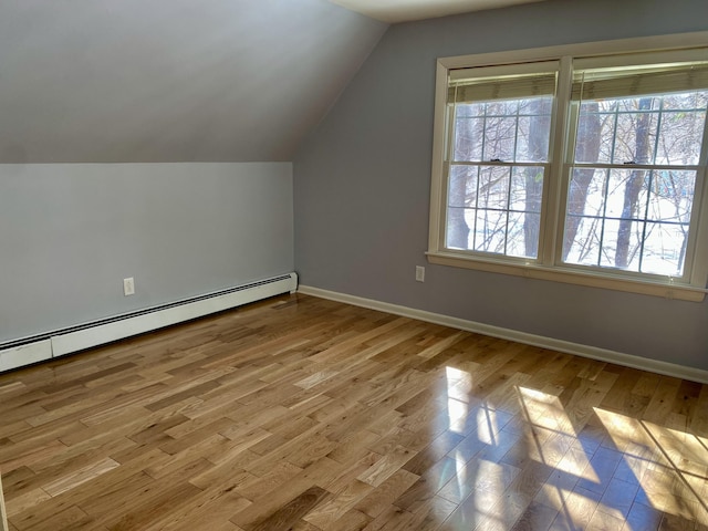 additional living space featuring vaulted ceiling, plenty of natural light, light wood-style flooring, and baseboards