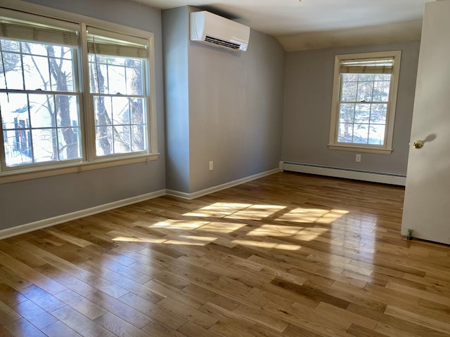 unfurnished room with a wall unit AC, baseboard heating, vaulted ceiling, light wood-type flooring, and baseboards