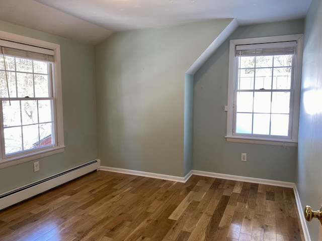 bonus room featuring a baseboard heating unit, a wealth of natural light, lofted ceiling, and wood finished floors