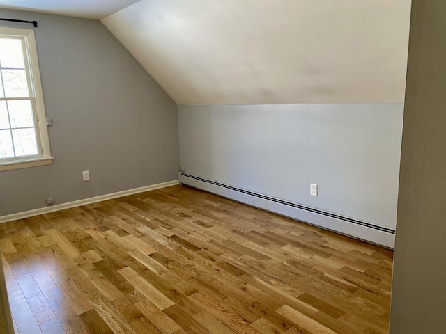 bonus room featuring light wood-style floors, a baseboard radiator, baseboards, and vaulted ceiling