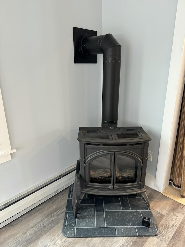 details with a baseboard heating unit, a wood stove, and wood finished floors