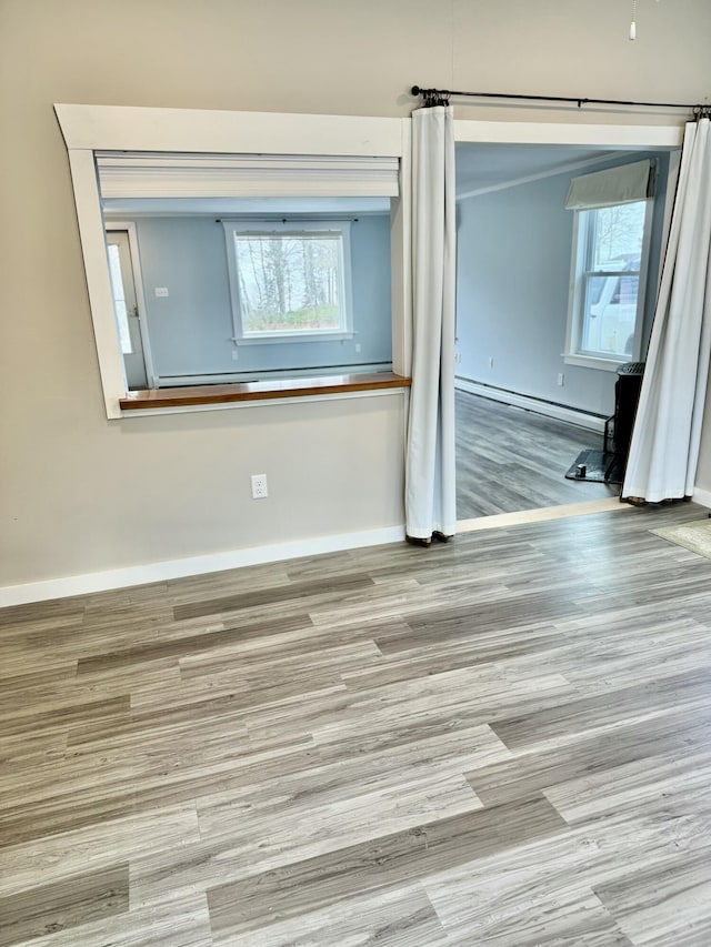 spare room featuring a baseboard radiator, baseboards, and wood finished floors