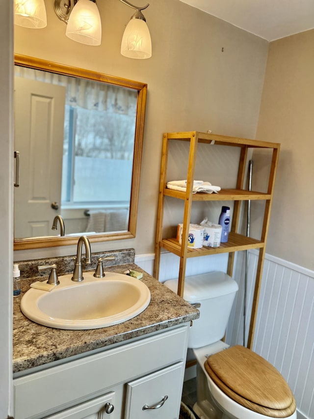 bathroom with wainscoting, vanity, and toilet