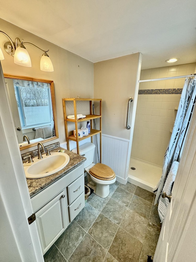 full bathroom with toilet, a wainscoted wall, a shower stall, and vanity