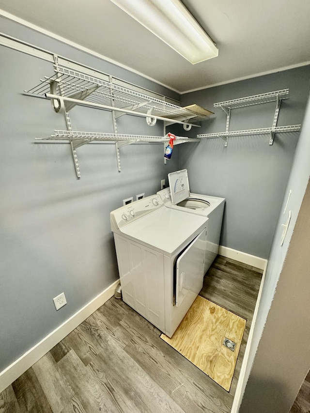 washroom featuring wood finished floors, laundry area, baseboards, and separate washer and dryer