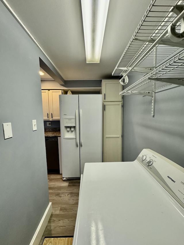 clothes washing area with washer / clothes dryer, cabinet space, dark wood finished floors, and baseboards