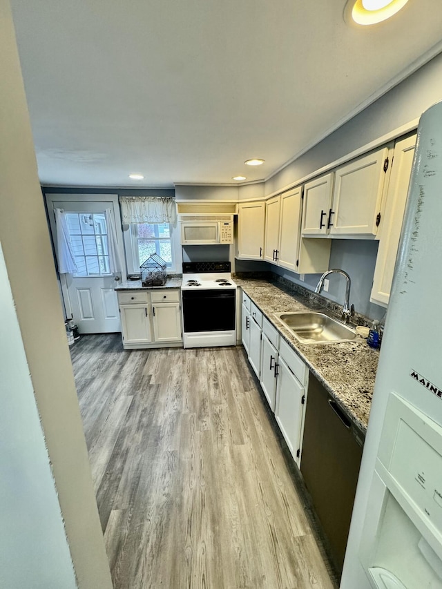 kitchen featuring white microwave, white cabinetry, a sink, light wood-type flooring, and range with electric cooktop