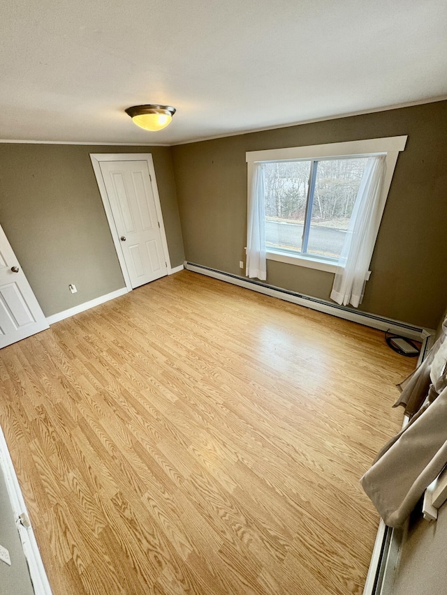 interior space featuring baseboard heating, wood finished floors, and baseboards