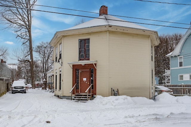 view of front of house featuring entry steps, fence, and a chimney