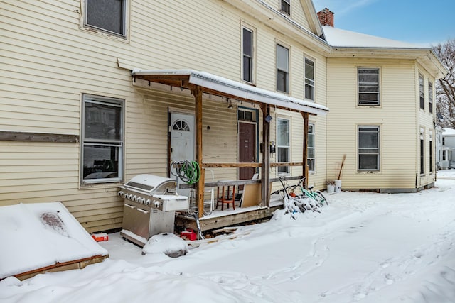 snow covered property entrance with a chimney