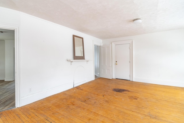 spare room with a textured ceiling, baseboards, and wood finished floors