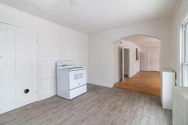 unfurnished room featuring radiator, light wood-style flooring, and arched walkways