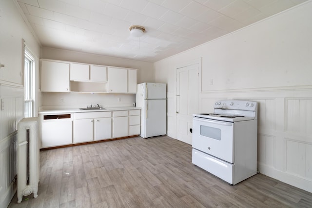 kitchen with light wood finished floors, light countertops, white cabinetry, a sink, and white appliances