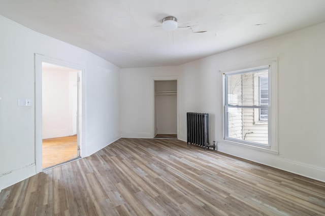 unfurnished room with light wood finished floors, radiator heating unit, and baseboards