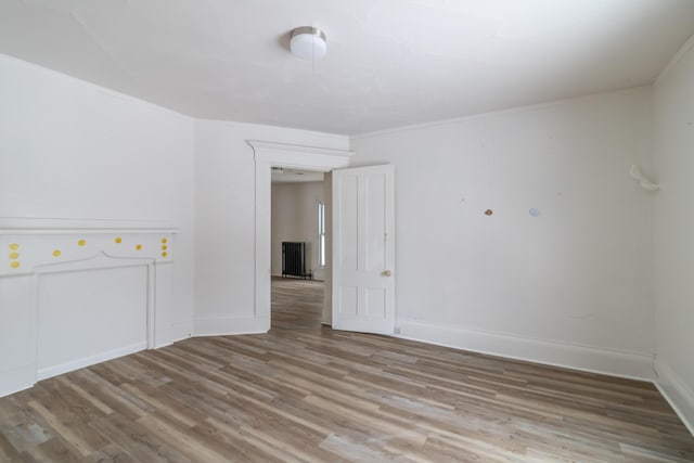 spare room featuring baseboards, wood finished floors, and crown molding